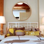 Round mirror above the head of the bed